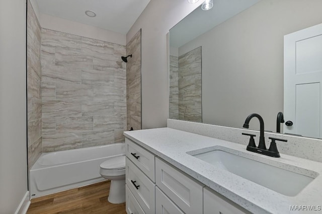 full bathroom with vanity, tiled shower / bath, hardwood / wood-style floors, and toilet