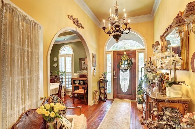 entryway with a notable chandelier, wood-type flooring, and ornamental molding