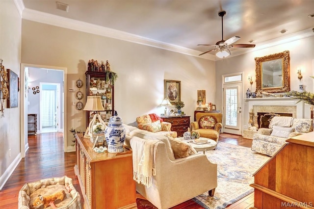 living room featuring ceiling fan, crown molding, wood-type flooring, and a fireplace