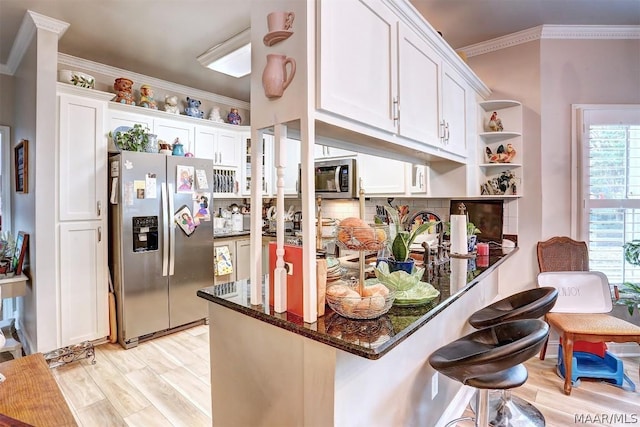 kitchen with kitchen peninsula, dark stone countertops, white cabinetry, and stainless steel appliances