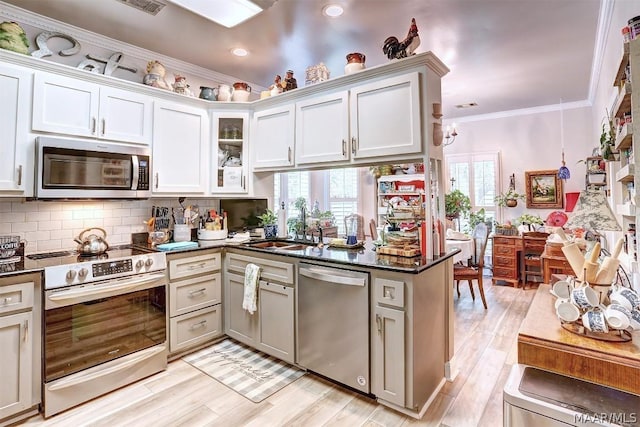 kitchen featuring white cabinets, light hardwood / wood-style flooring, ornamental molding, appliances with stainless steel finishes, and kitchen peninsula