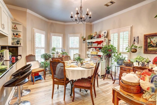 dining area featuring light hardwood / wood-style flooring, ornamental molding, and a notable chandelier