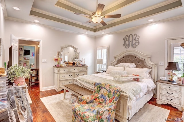 bedroom featuring light wood-type flooring, a raised ceiling, ceiling fan, and crown molding