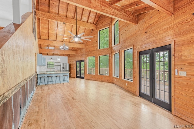 unfurnished living room with wooden ceiling, light wood-type flooring, ceiling fan, high vaulted ceiling, and beam ceiling