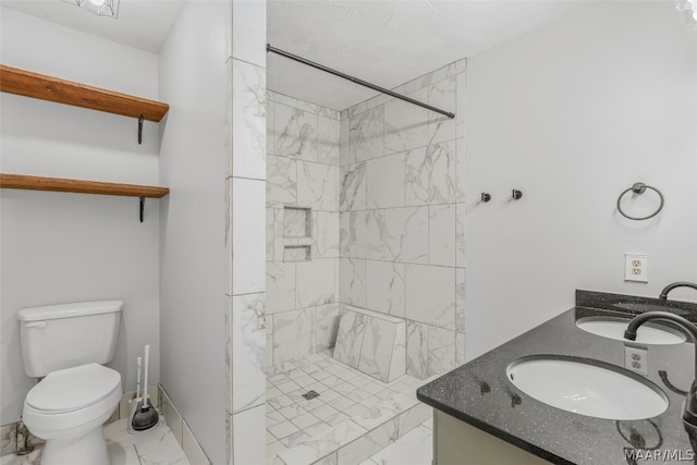 bathroom with vanity, toilet, and tiled shower