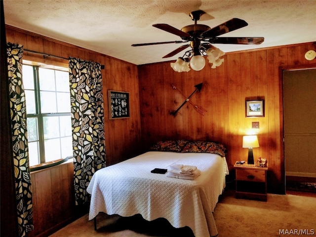 bedroom featuring wooden walls, multiple windows, ceiling fan, and carpet flooring