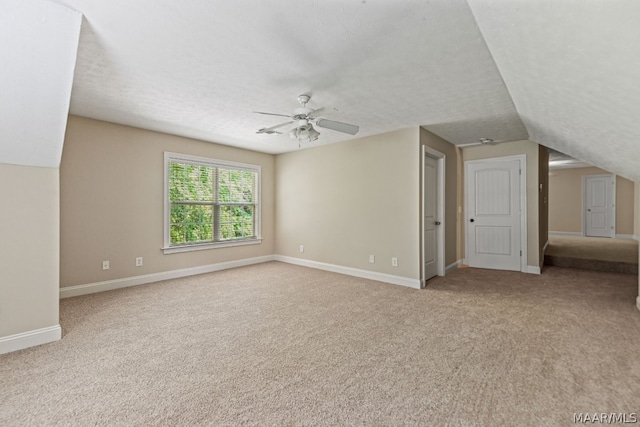 interior space with light carpet, a textured ceiling, vaulted ceiling, and ceiling fan