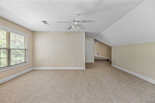 additional living space featuring ceiling fan, light colored carpet, lofted ceiling, and a textured ceiling