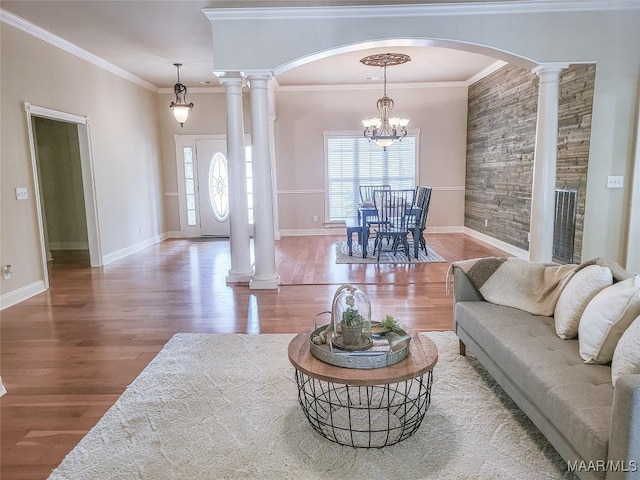 living room featuring a chandelier, hardwood / wood-style floors, ornate columns, and crown molding