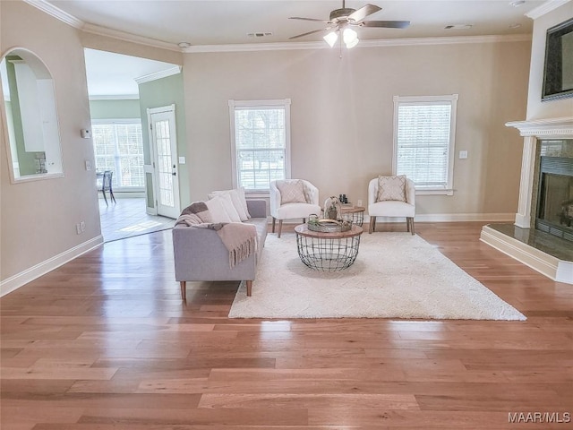 living room with crown molding, a fireplace, ceiling fan, and hardwood / wood-style flooring