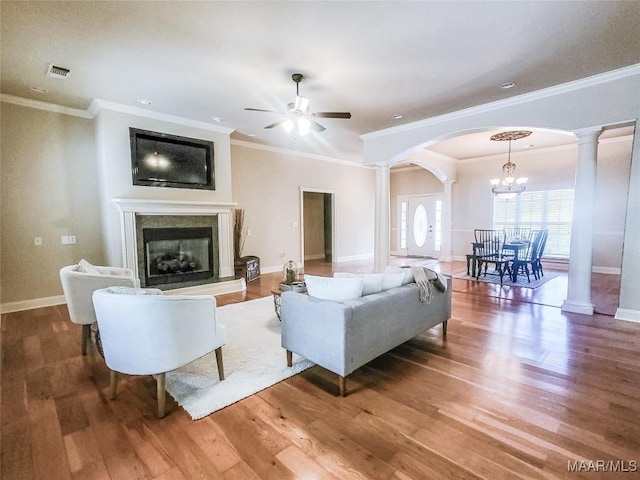 living room featuring hardwood / wood-style floors, ceiling fan with notable chandelier, decorative columns, and crown molding