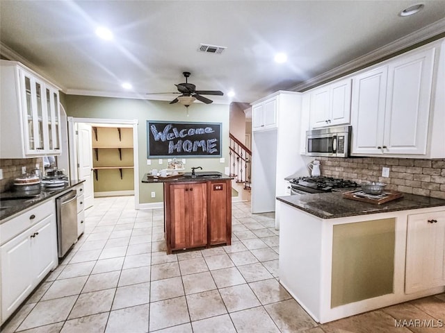 kitchen with tasteful backsplash, white cabinetry, stainless steel appliances, and ornamental molding