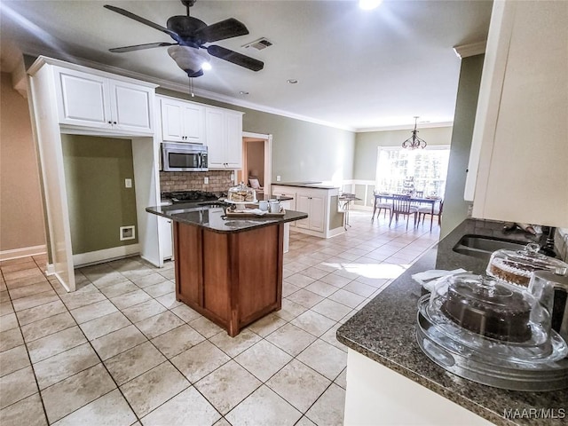 kitchen featuring backsplash, crown molding, sink, dark stone countertops, and white cabinets