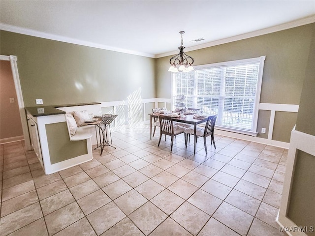 dining area with a notable chandelier, light tile patterned floors, and crown molding