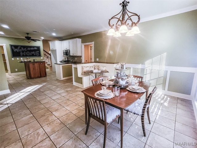 dining area with light tile patterned floors, ceiling fan with notable chandelier, and crown molding