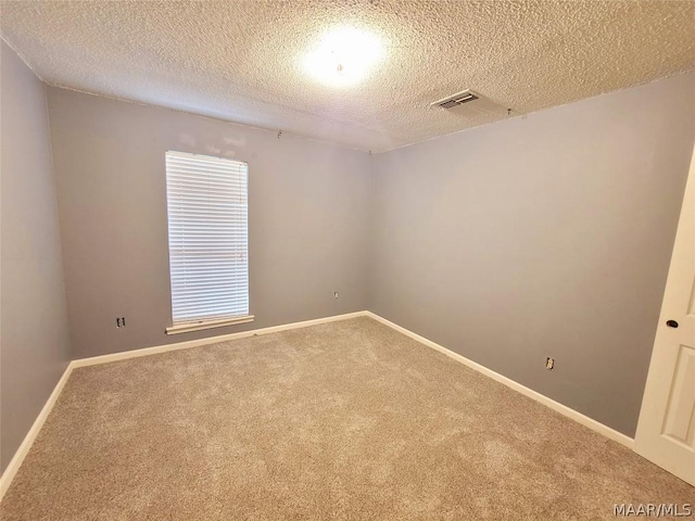 carpeted empty room featuring a textured ceiling