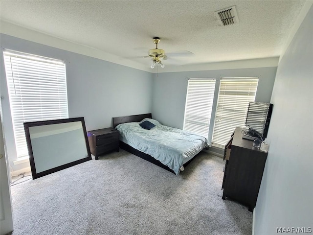 bedroom with ceiling fan, carpet floors, and a textured ceiling