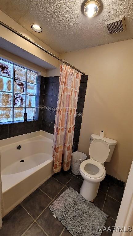 bathroom featuring toilet, tile patterned flooring, a textured ceiling, and shower / tub combo