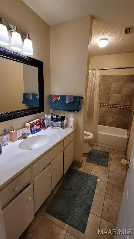 full bathroom featuring vanity, tile patterned flooring, shower / bath combo with shower curtain, and a textured ceiling