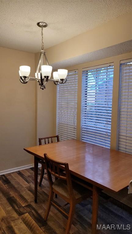 dining area featuring a textured ceiling, dark hardwood / wood-style floors, and a chandelier