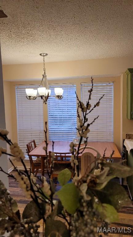 unfurnished dining area featuring a textured ceiling and a chandelier