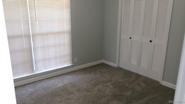 unfurnished bedroom featuring a closet and dark carpet