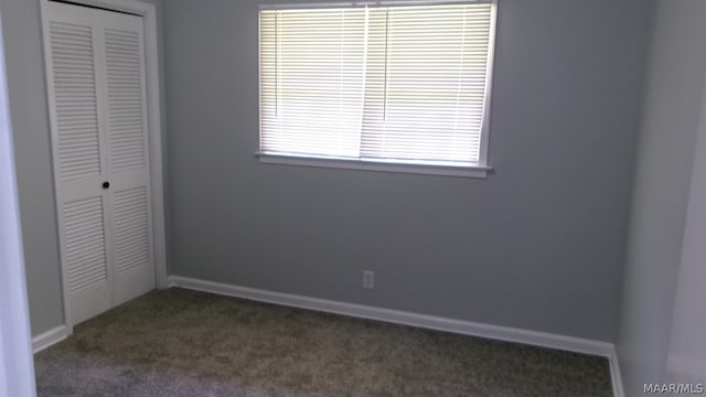 unfurnished bedroom with dark colored carpet and a closet