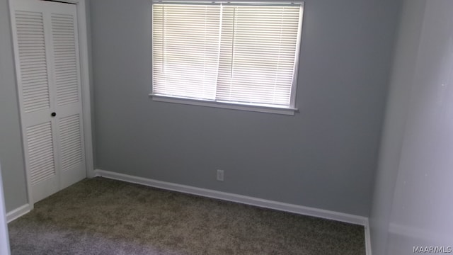 unfurnished bedroom featuring a closet and dark carpet