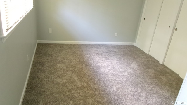 unfurnished bedroom with a closet and dark colored carpet