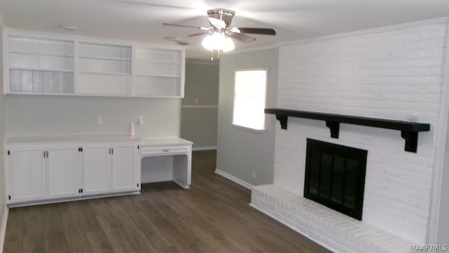 interior space featuring brick wall, a fireplace, ceiling fan, crown molding, and dark wood-type flooring