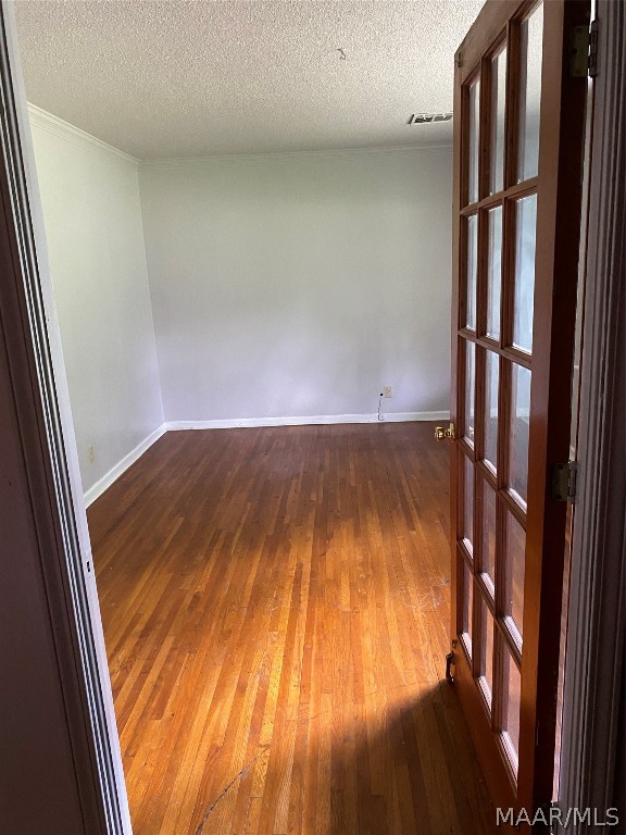 empty room with hardwood / wood-style flooring and a textured ceiling