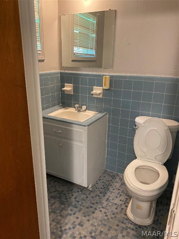 bathroom with tile walls, toilet, vanity, and tile patterned flooring