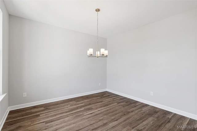 empty room featuring dark hardwood / wood-style flooring and an inviting chandelier