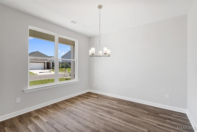 unfurnished room with hardwood / wood-style floors and a notable chandelier