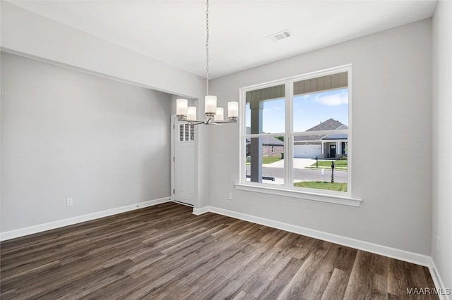 unfurnished dining area with dark wood-type flooring and an inviting chandelier