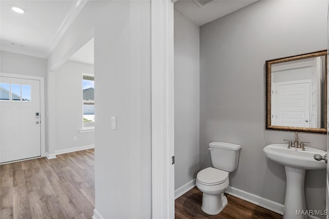 bathroom featuring hardwood / wood-style floors, toilet, and crown molding