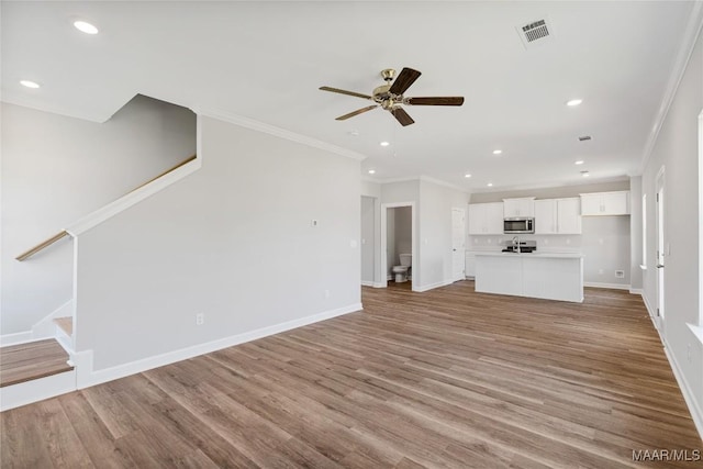 unfurnished living room featuring light wood-type flooring, ceiling fan, and crown molding