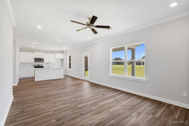 unfurnished living room featuring ceiling fan, sink, ornamental molding, and hardwood / wood-style flooring