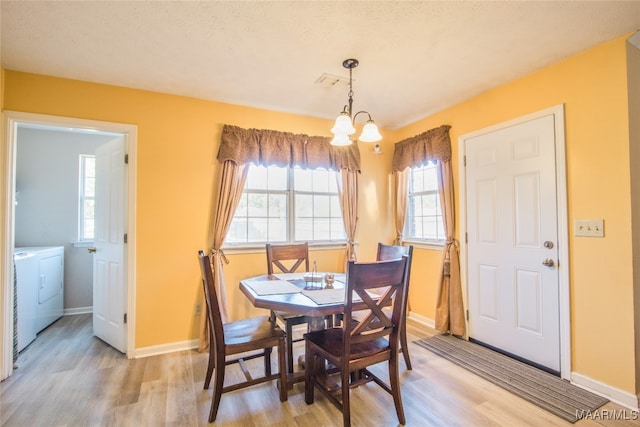 dining area with washer and clothes dryer, light hardwood / wood-style floors, a chandelier, and plenty of natural light