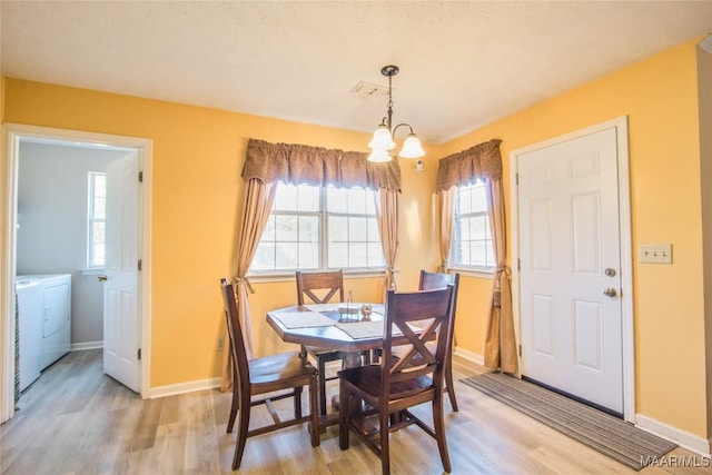 dining space featuring visible vents, baseboards, a notable chandelier, light wood-style flooring, and washing machine and dryer