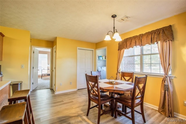 dining area featuring light wood finished floors, washing machine and clothes dryer, baseboards, and visible vents
