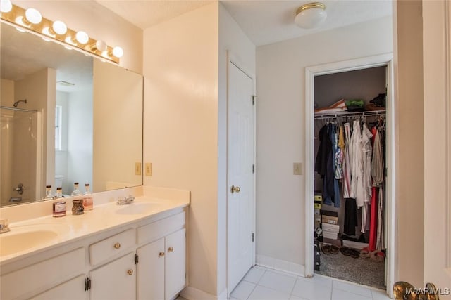 bathroom featuring toilet, double vanity, a sink, and walk in shower