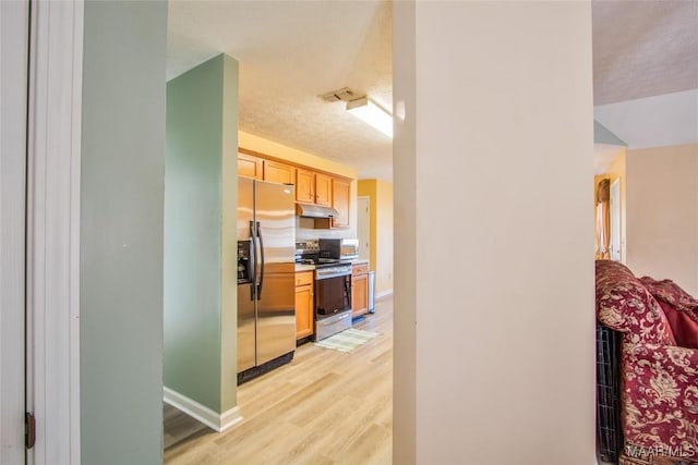 kitchen featuring baseboards, under cabinet range hood, light wood-style floors, visible vents, and appliances with stainless steel finishes
