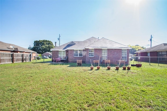 back of house featuring brick siding, a fenced backyard, and a lawn
