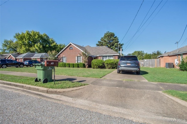 view of front of home with cooling unit, driveway, a front yard, and fence