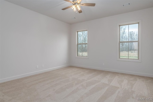 unfurnished room featuring ceiling fan, plenty of natural light, and light carpet