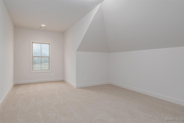 bonus room with vaulted ceiling and light colored carpet