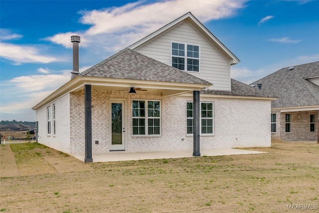 rear view of house with a patio, roof with shingles, ceiling fan, a lawn, and brick siding