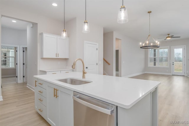 kitchen with a sink, light wood finished floors, stainless steel dishwasher, and light countertops