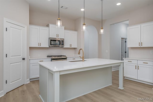 kitchen featuring appliances with stainless steel finishes, light countertops, light wood-style floors, and a sink